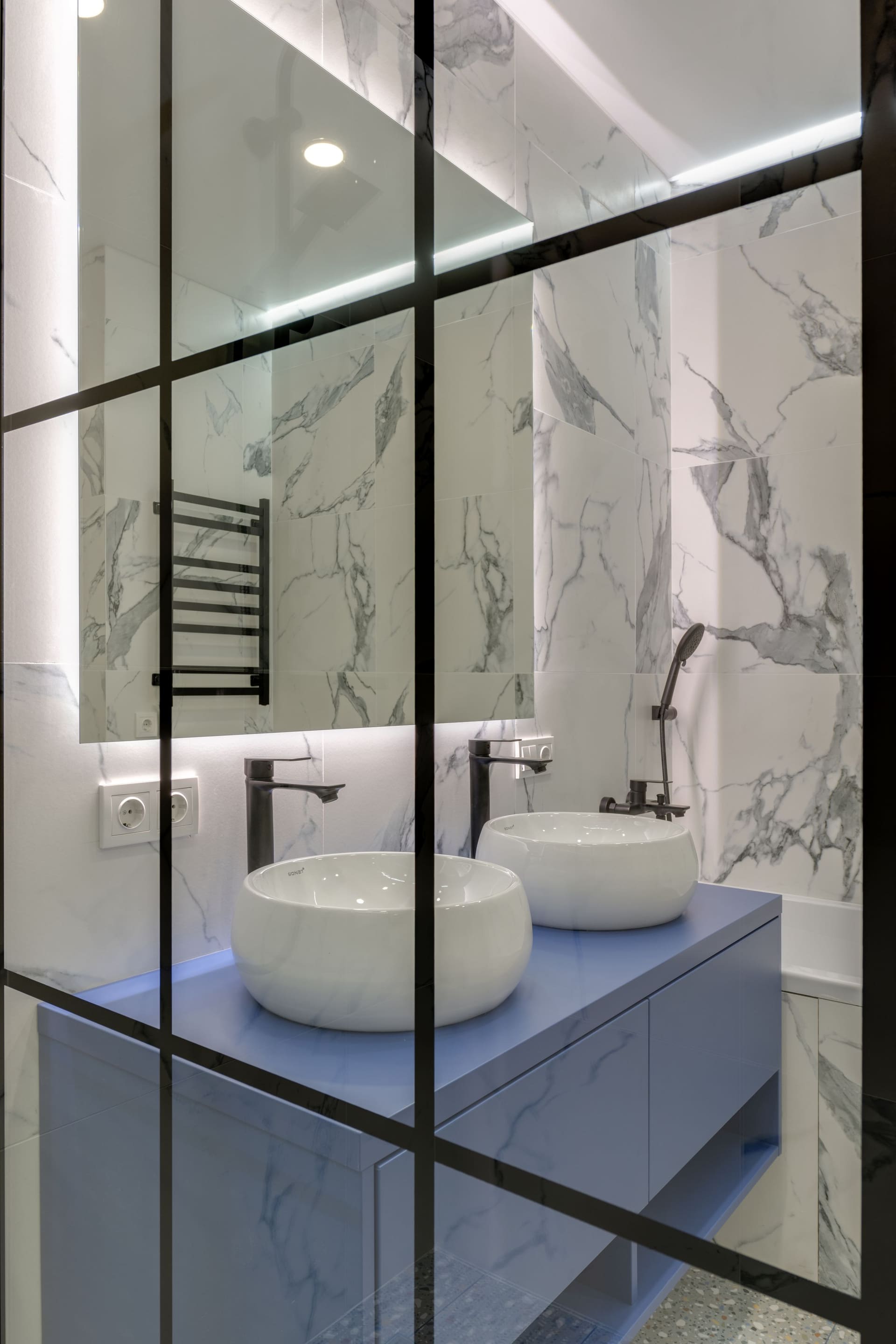 The finished bathroom with a double vanity and marble walls